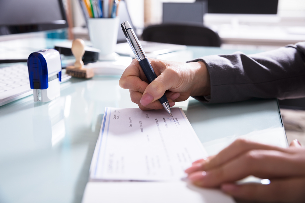 Businessperson Signing Cheque In Office